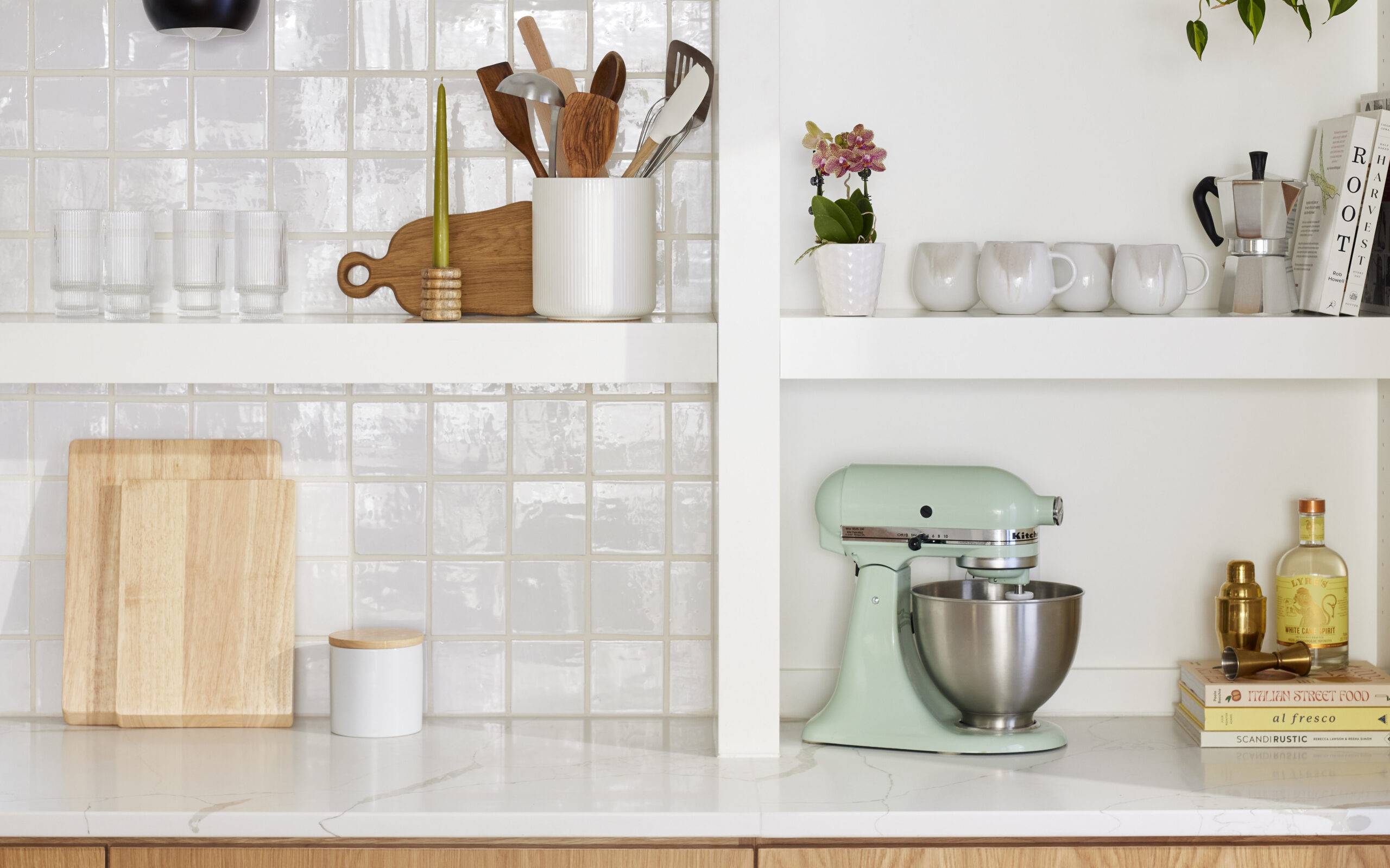 This bright and charming kitchen features white Zellige tile backsplash and open white shelves. 