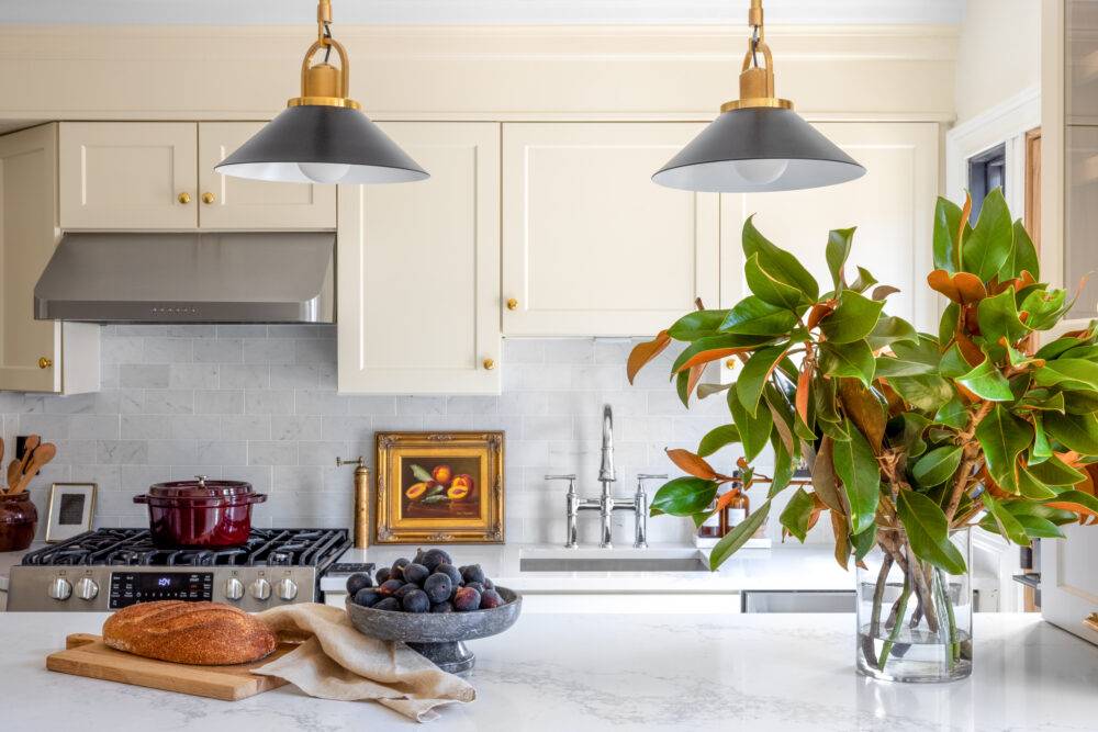 This homey kitchen features a white marble subway tile backsplash and cream-colored cabinets. 