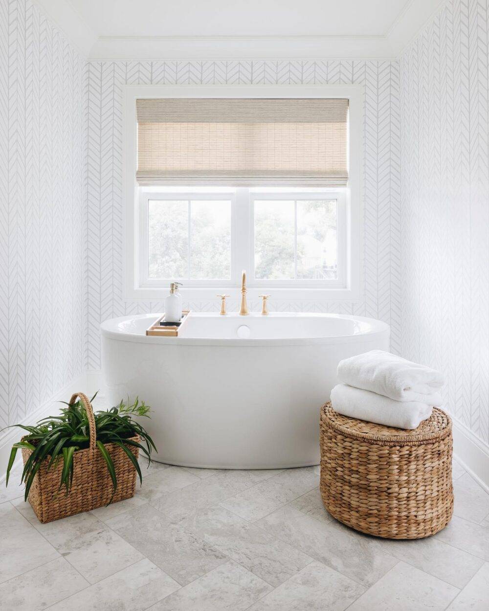 This bright white bathroom features large-format white marble tile in a herringbone pattern. 