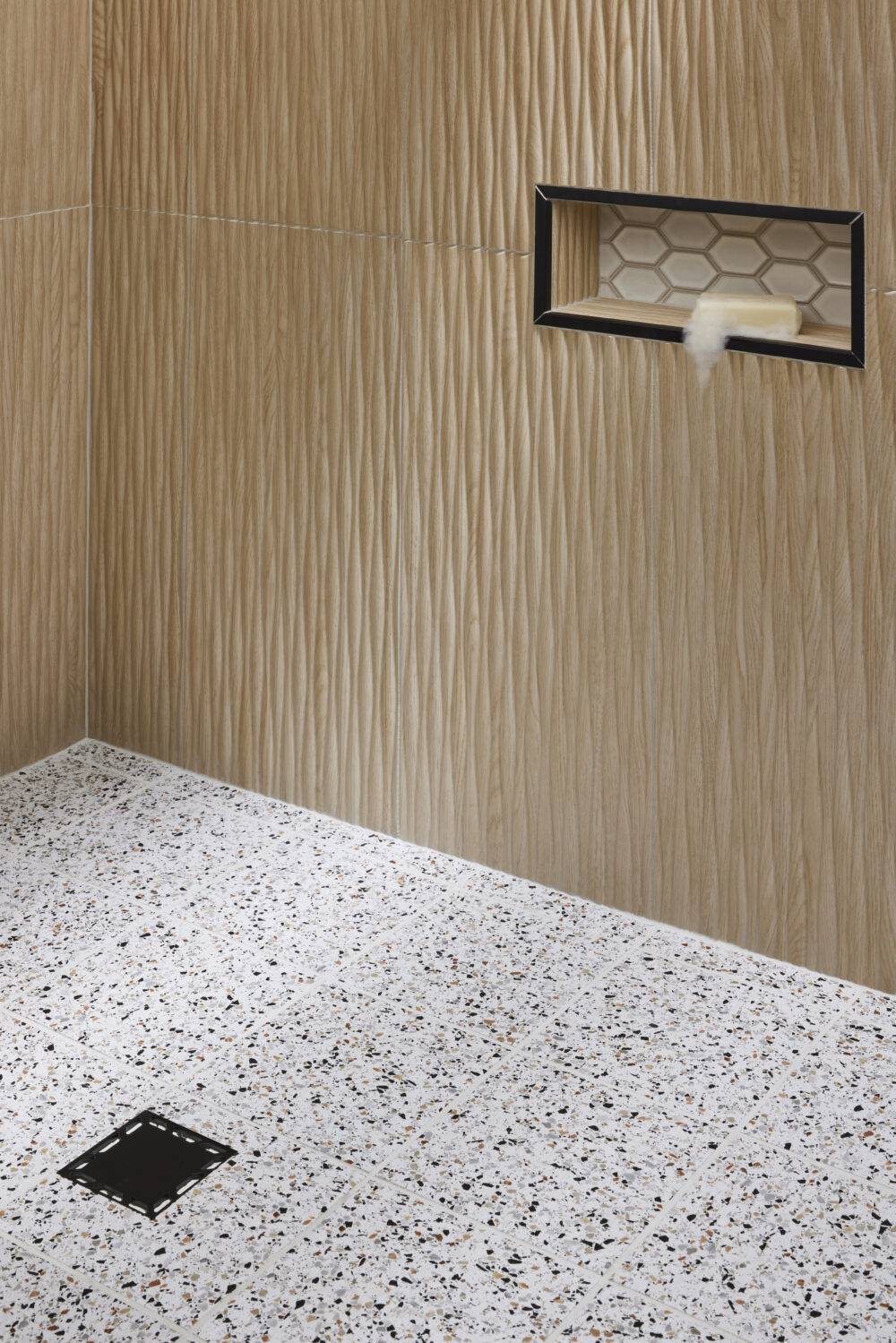 This chic shower features terrazzo tile floor and wood-look fluted wall tile. 