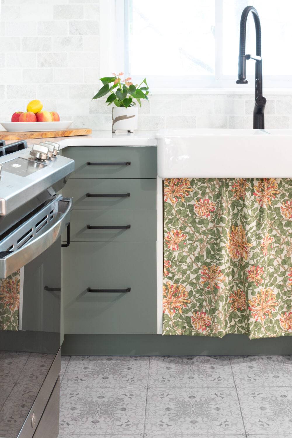 This charming kitchen features a black and grey ornate floral patterned floor tile and marble subway tile backsplash. 