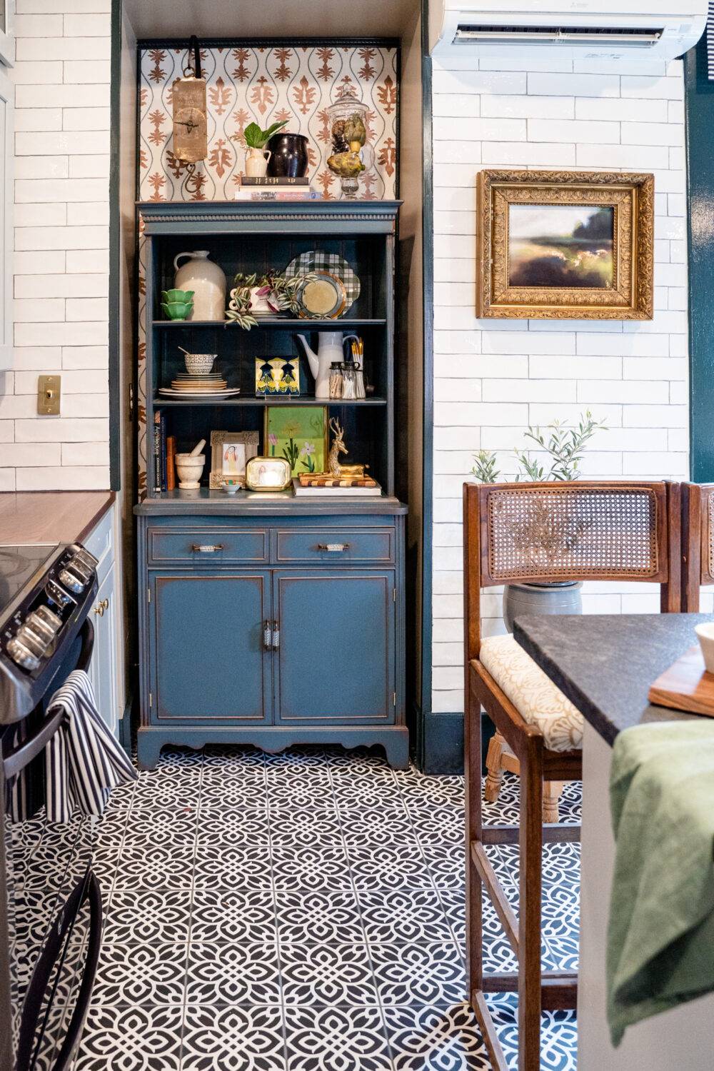 This cozy kitchen features a black-and-white patterned tile floor and white subway tile walls. 